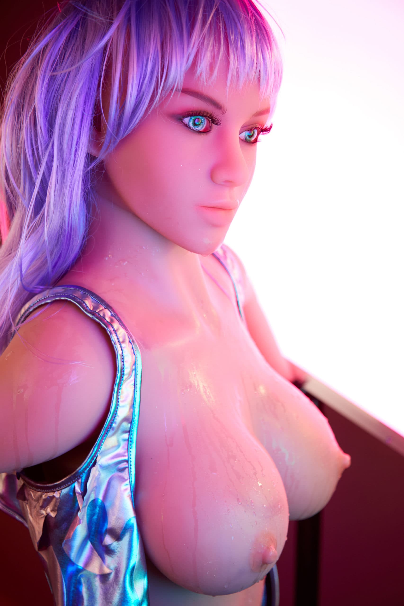 TPE sex doll Techno Babe with shiny bare breasts and purple hair – side view in metallic outfit and neon lighting